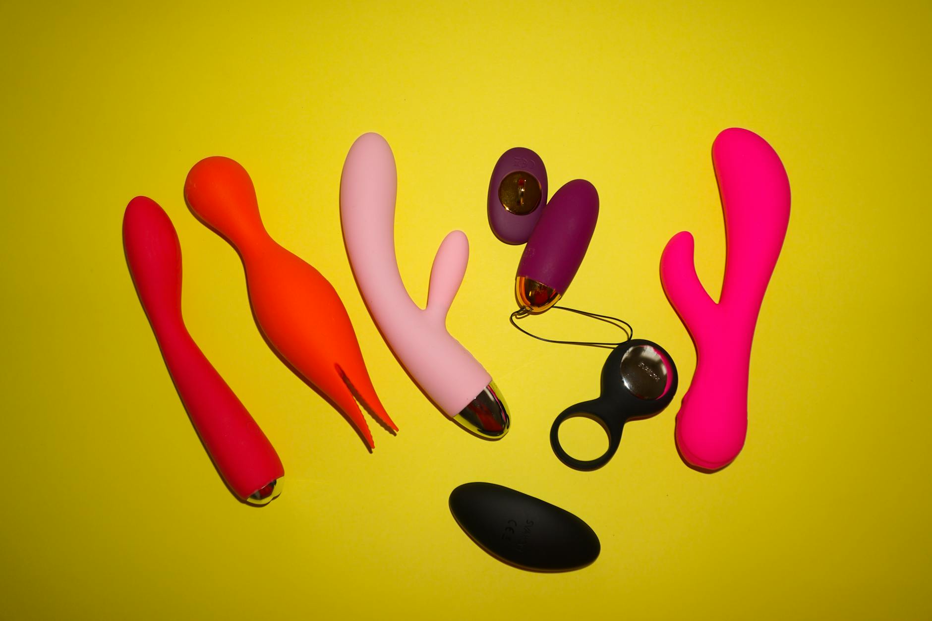 Pink vibrator arranged with heart confetti and candles, symbolizing intimate pleasure and communication with a partner